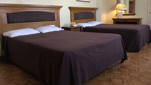 Habitación de hotel con dos camas, una mesita de noche con teléfono, un espejo y cuadros en las paredes.