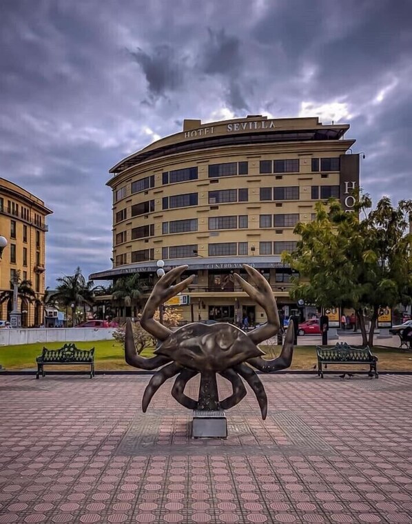 A large building labeled "HOTEL SEVILLA" with a prominent crab sculpture in front.