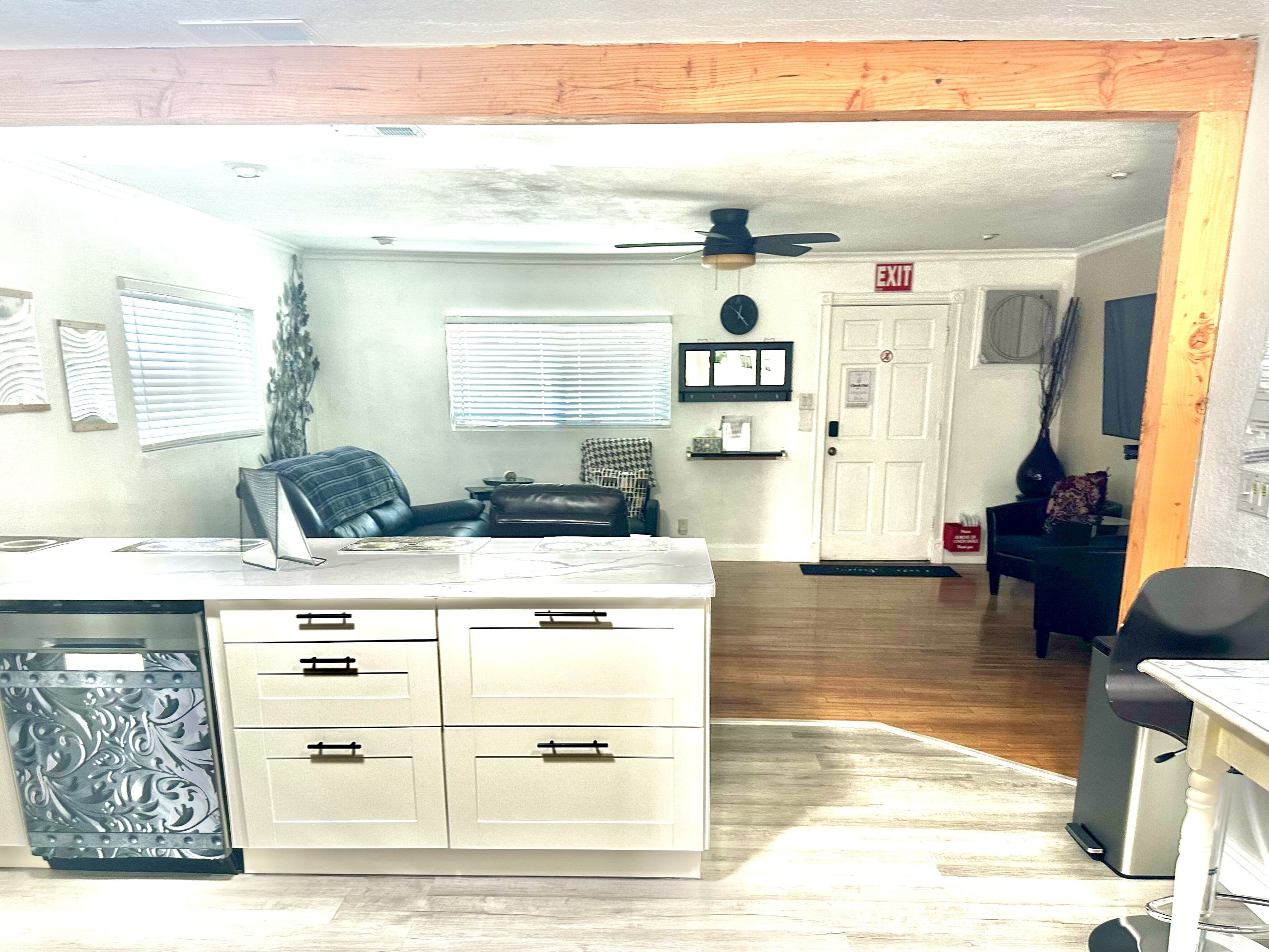 A compact kitchen with white cabinets, a black chair, and a dining table.
