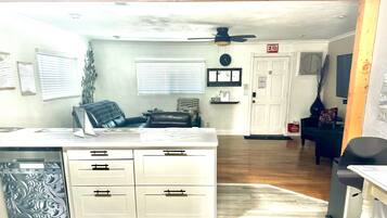A compact kitchen with white cabinets, a black chair, and a dining table.