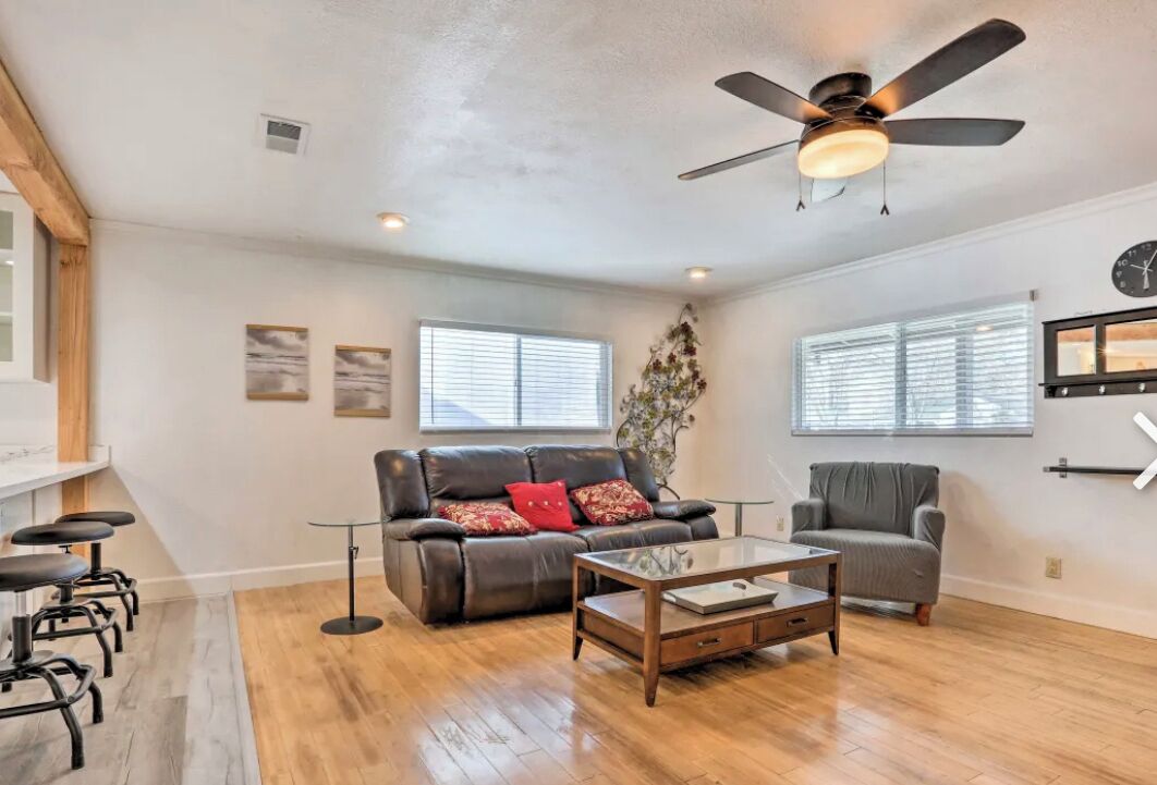 A spacious living room with a ceiling fan, a sofa, a chair, a coffee table, and a TV.