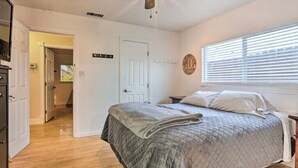A bedroom with a bed, a ceiling fan, a door, and a window with blinds.