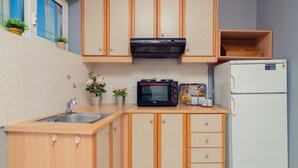 Eine kleine Küche mit Holzausstattung, einer eingebauten Mikrowelle, einem Kühlschrank und einem Spülbecken.