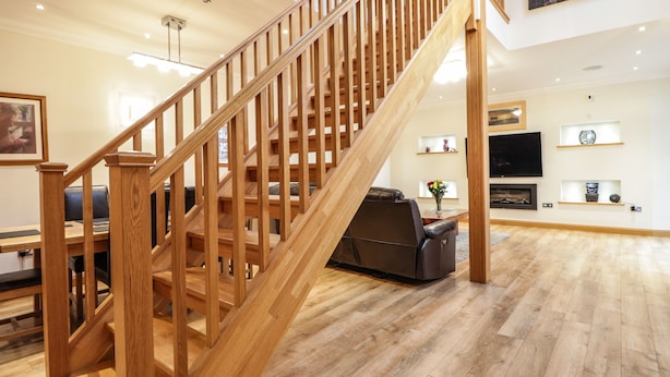 A wooden staircase leading to a living area with a flat-screen TV, a fireplace, and a dining table. - 1 The Coach House (Elgin)