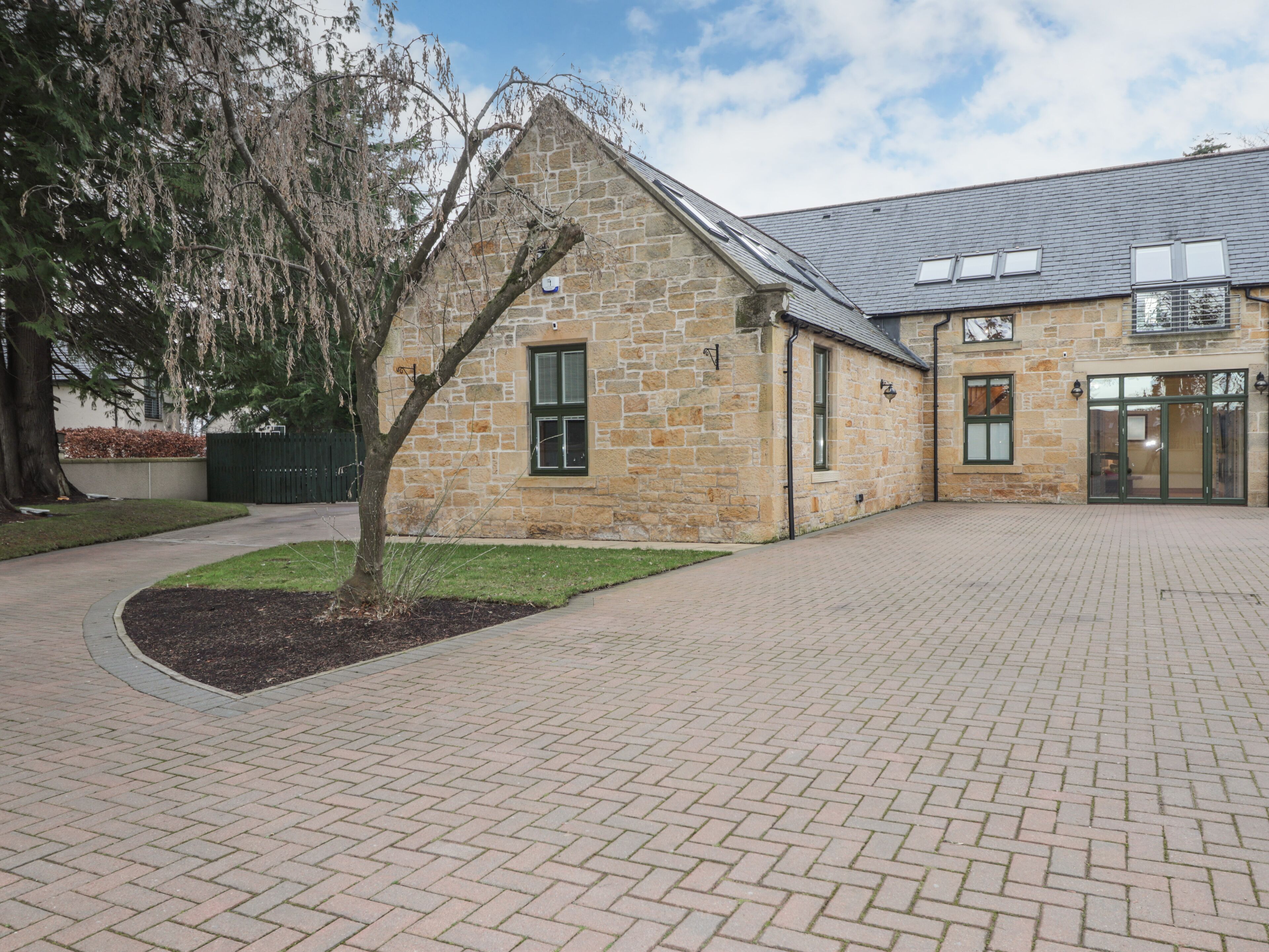 A stone building with a brick pathway leading to a gated entrance.