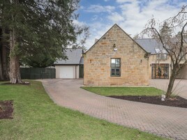 A stone building with a garage, a paved driveway, and a well-maintained lawn.