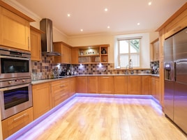 A modern kitchen with wooden cabinets, stainless steel appliances, and a tiled backsplash.