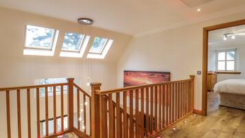 A spacious room with a wooden staircase, skylights, and a large painting on the wall.