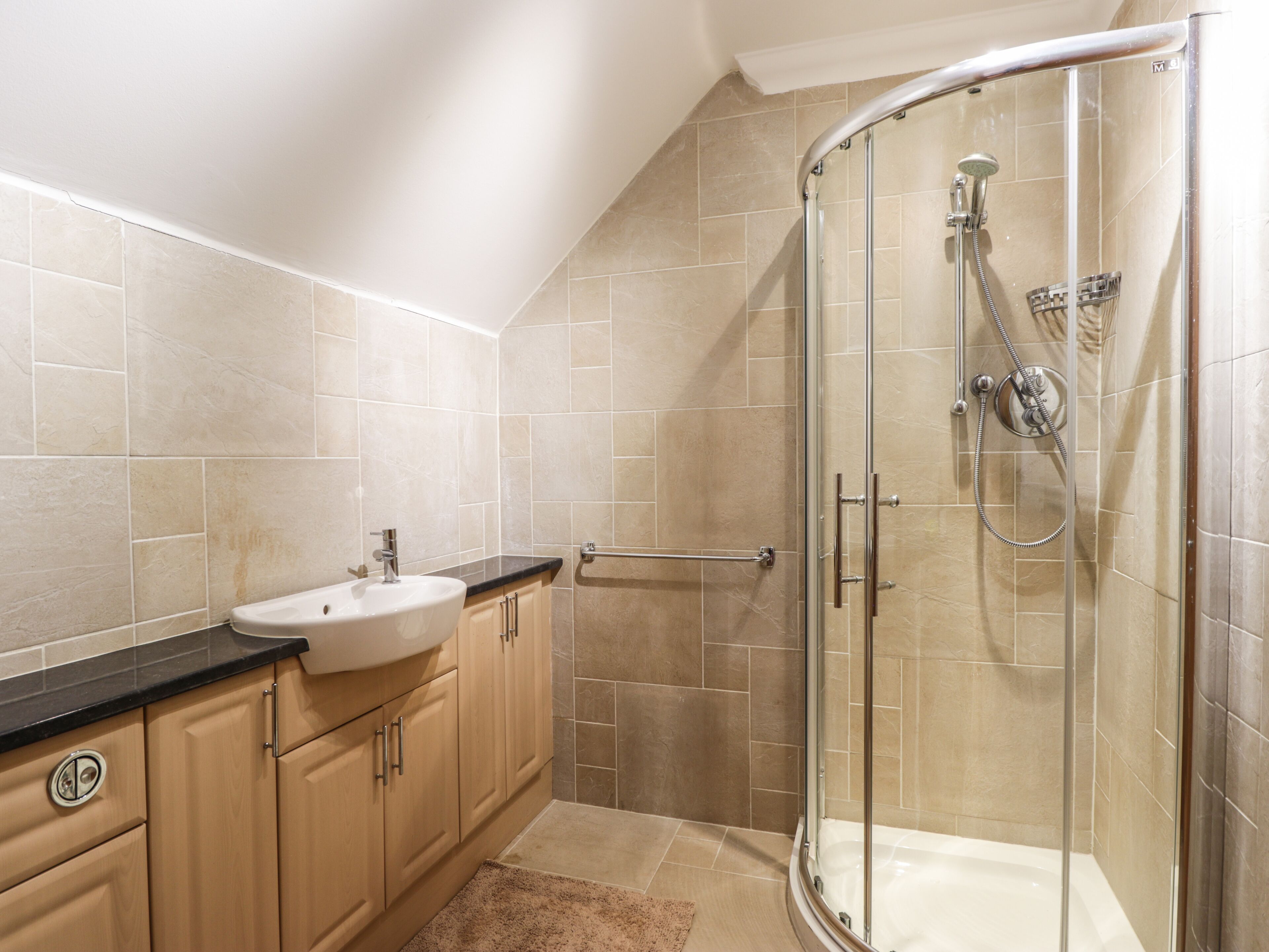 Un baño moderno con cabina de ducha de vidrio, un lavamanos y armarios de madera.