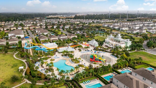 Una zona residencial con una piscina grande, toboganes de agua y un parque infantil.