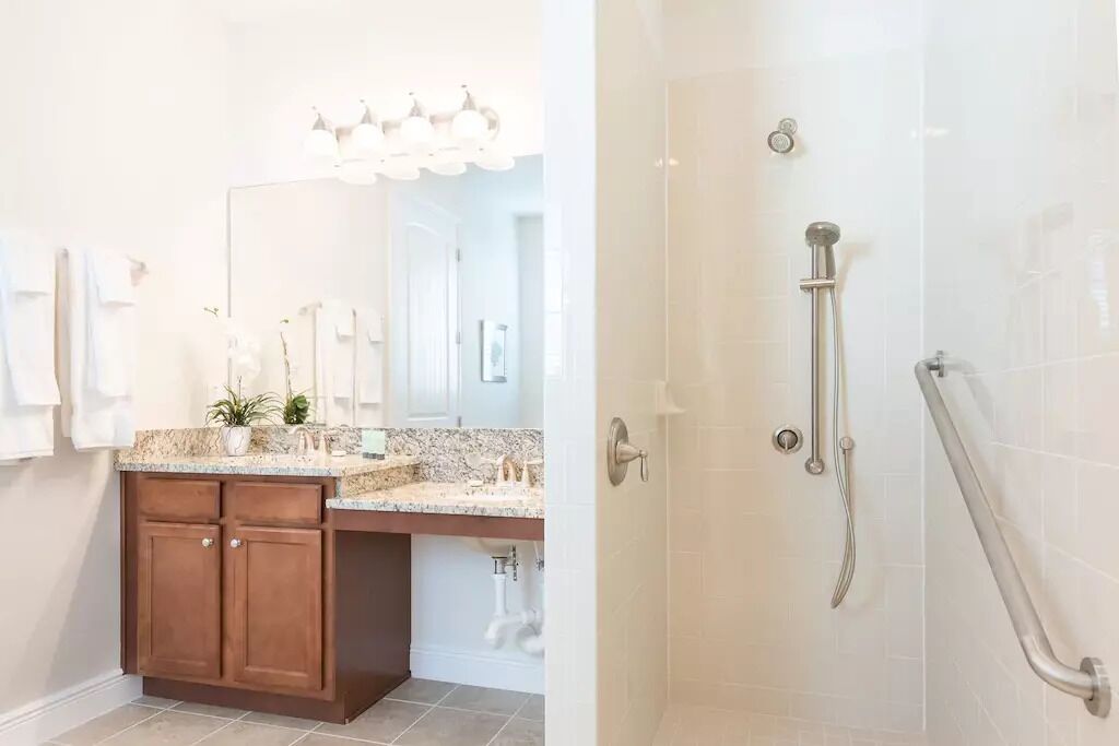 A bathroom with a shower, a sink, and a vanity with cabinets.