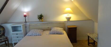 A bedroom with a bed, bedside lamps, a nightstand, a chair, and a small table.