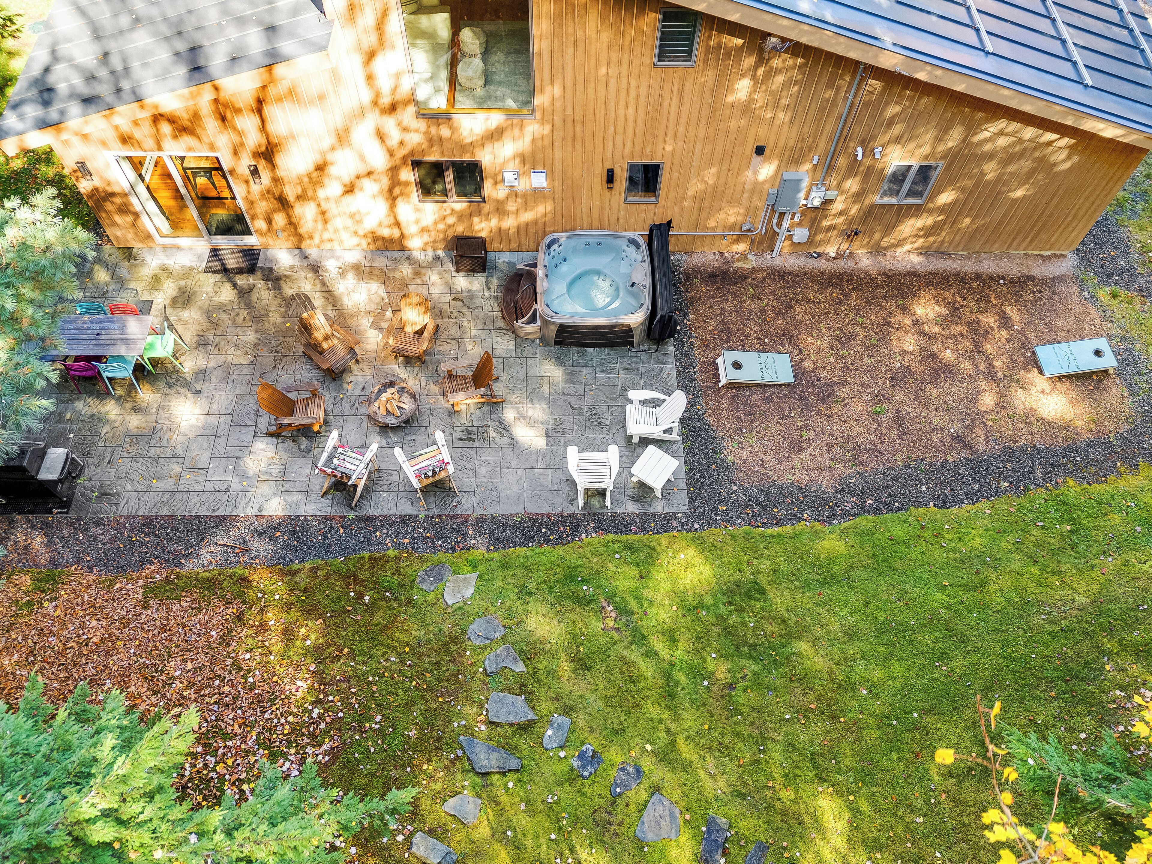 Una casa de madera con jacuzzi, mobiliario exterior y una chimenea de piedra.