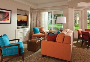 A hotel room with a sofa set, a television, a lamp, and a view of a golf course. - Marriott's Desert Springs Villas II Resort (Palm Desert)