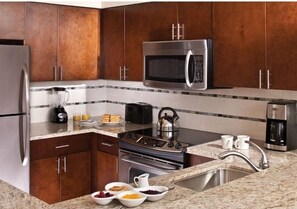 A kitchen with dark wooden cabinets, stainless steel appliances, and a granite countertop. - Marriott's Desert Springs Villas II Resort (Palm Desert)