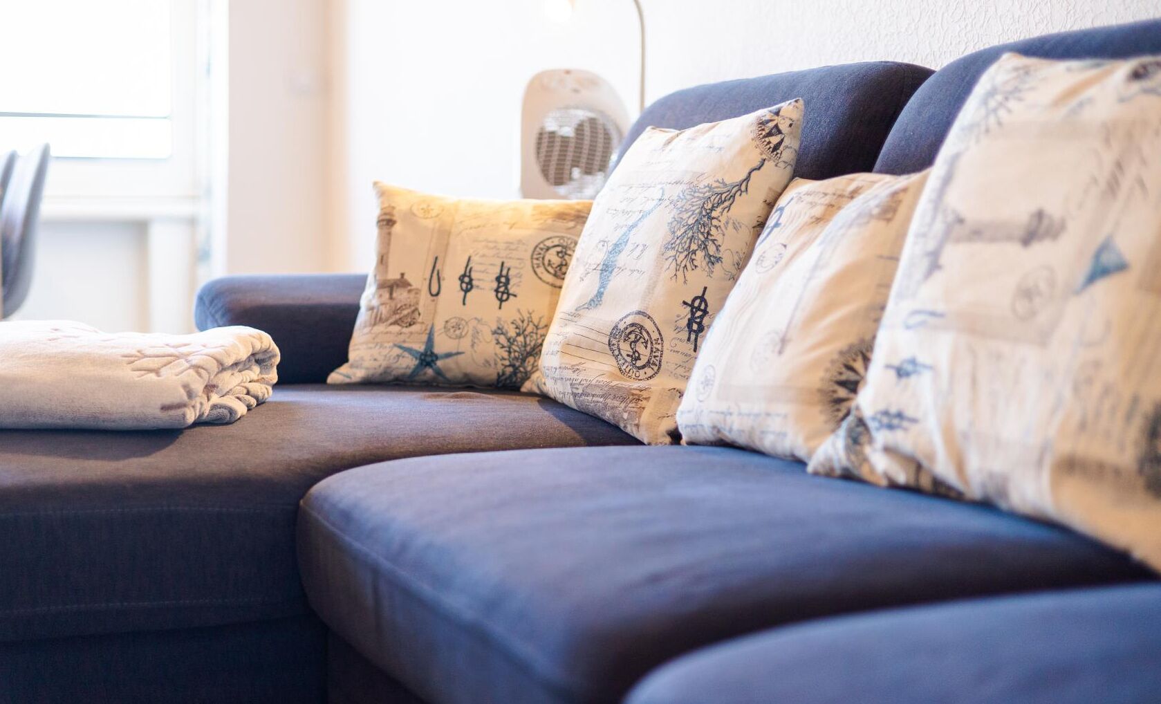 Un sofá de color oscuro con varios cojines decorativos con diseños de estilo vintage.