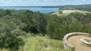 Eine Küstenlandschaft mit üppiger Vegetation, einer Steinsichtmauer und Blick auf das Meer.