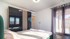 A bedroom with a bed, a large mirror, a wardrobe, and a sliding glass door to a balcony. - Luxurious villa with private pool and sun terrace (Valbandon)