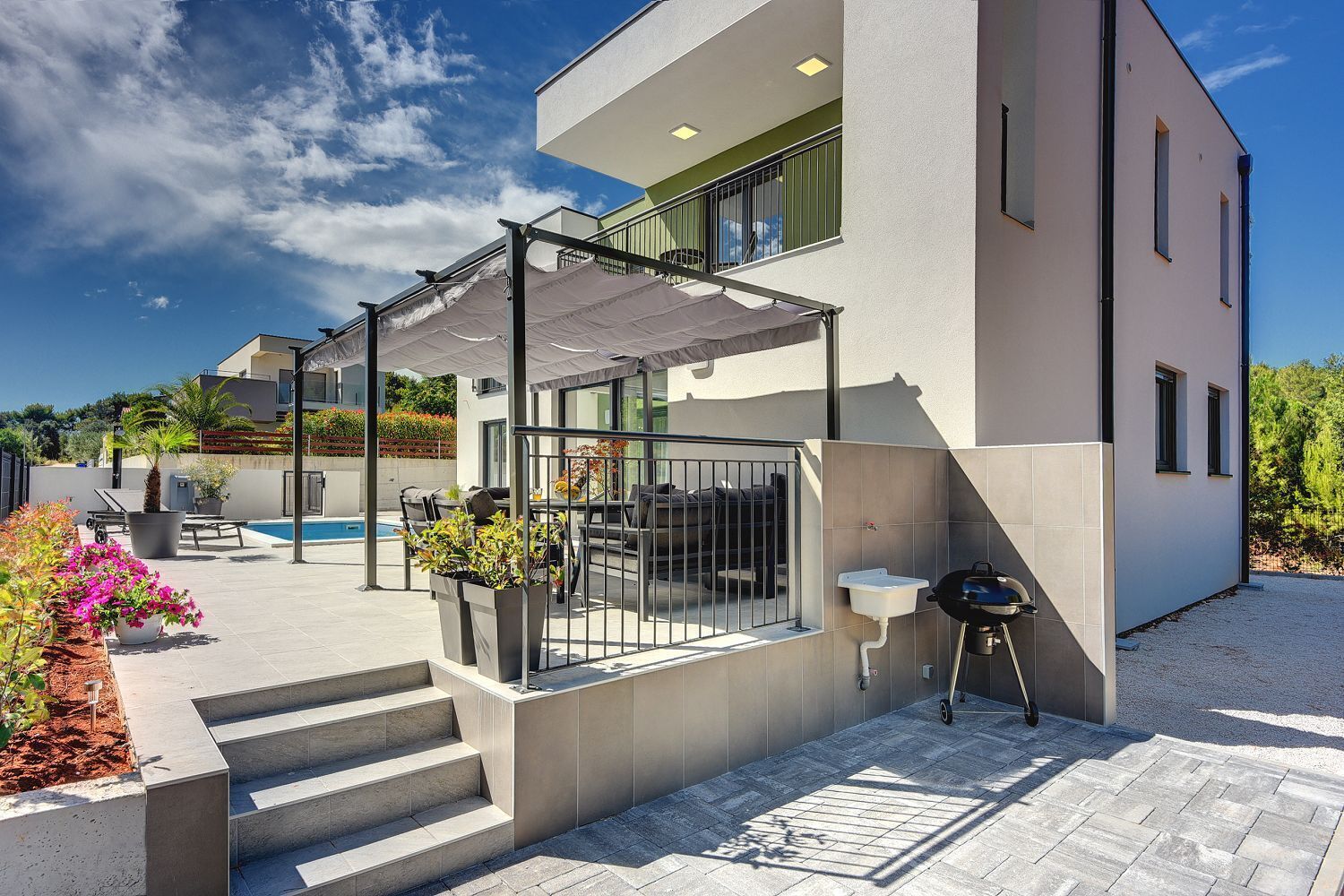 A modern house with a covered outdoor area, a pool, and outdoor seating.