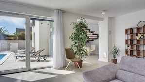A modern living room with a grey sofa, a large potted plant, and a staircase leading to an upper floor. - Modern villa with private pool, sun terrace only 2 km from the beach (Medulin)
