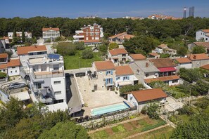 Zona residencial con casas, piscina y una colina con árboles.