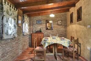 A rustic dining area with a brick wall, wooden ceiling, and a table set for two with a patterned tablecloth. - Villa with private pool, air conditioning, WiFi, BBQ and good location (Vodnjan)