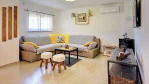 A living room with a sofa, coffee table, and stools. There is a fireplace with a mantel and a small table with decorative items. - Holiday home with badminton and mini football pitch (Pula)
