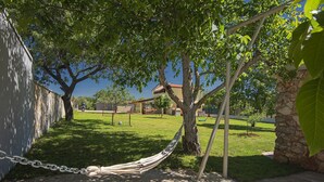 A hammock tied between trees in a grassy area with a building in the background. - Holiday home with badminton and mini football pitch (Pula)