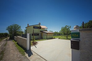 A two-story house with a paved driveway and a small garden. - Holiday home with badminton and mini football pitch (Pula)