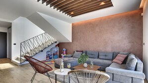 A modern living room with a staircase, grey sofa, and a coffee table. - 700 metres to the beach with private pool, WiFi, sea view (Medulin)