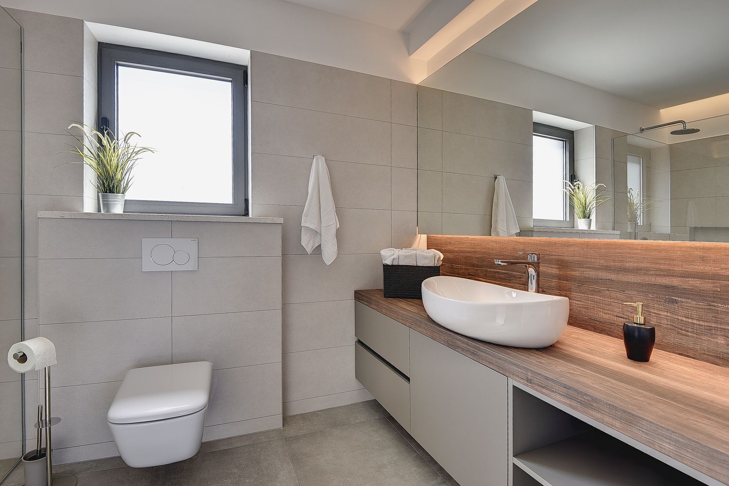 A modern bathroom with a toilet, sink, and mirror.