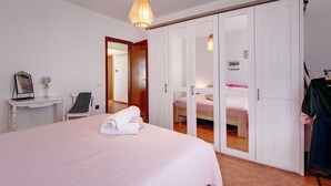 Una camera da letto con un letto grande, una scrivania con uno specchio, un armadio e una lampada a sospensione.