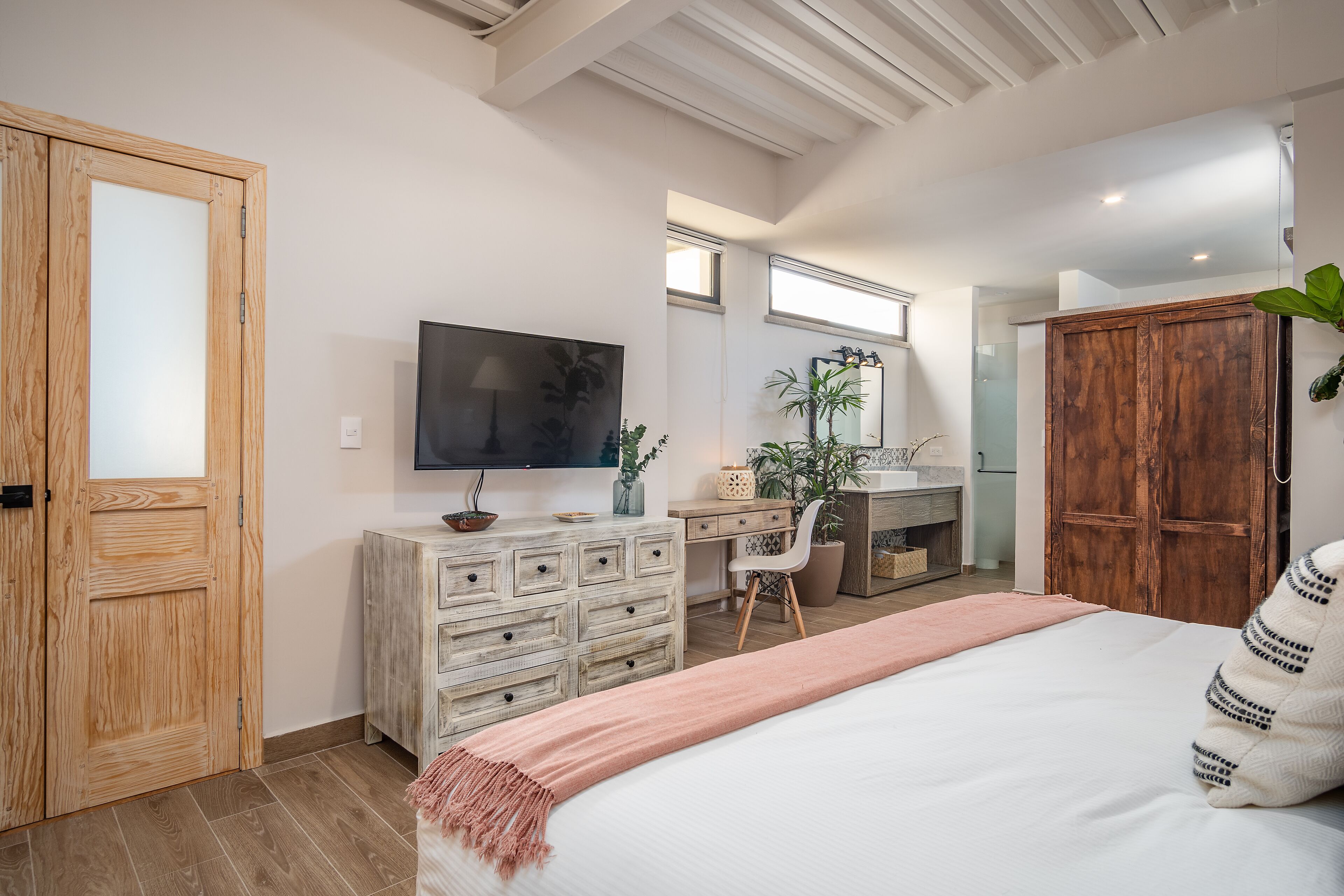 A bedroom with a bed, a desk, a television, and a wardrobe.
