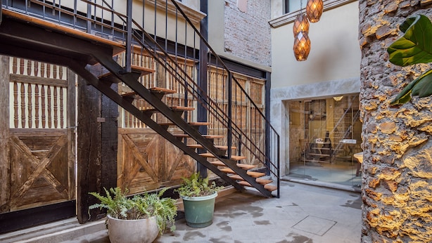 A staircase with wooden steps and metal railings, leading to a second floor. There are potted plants on the ground floor. - Casa Pandurata Luxury Apartments in Centro, San Miguel de Allende (San Miguel de Allende)