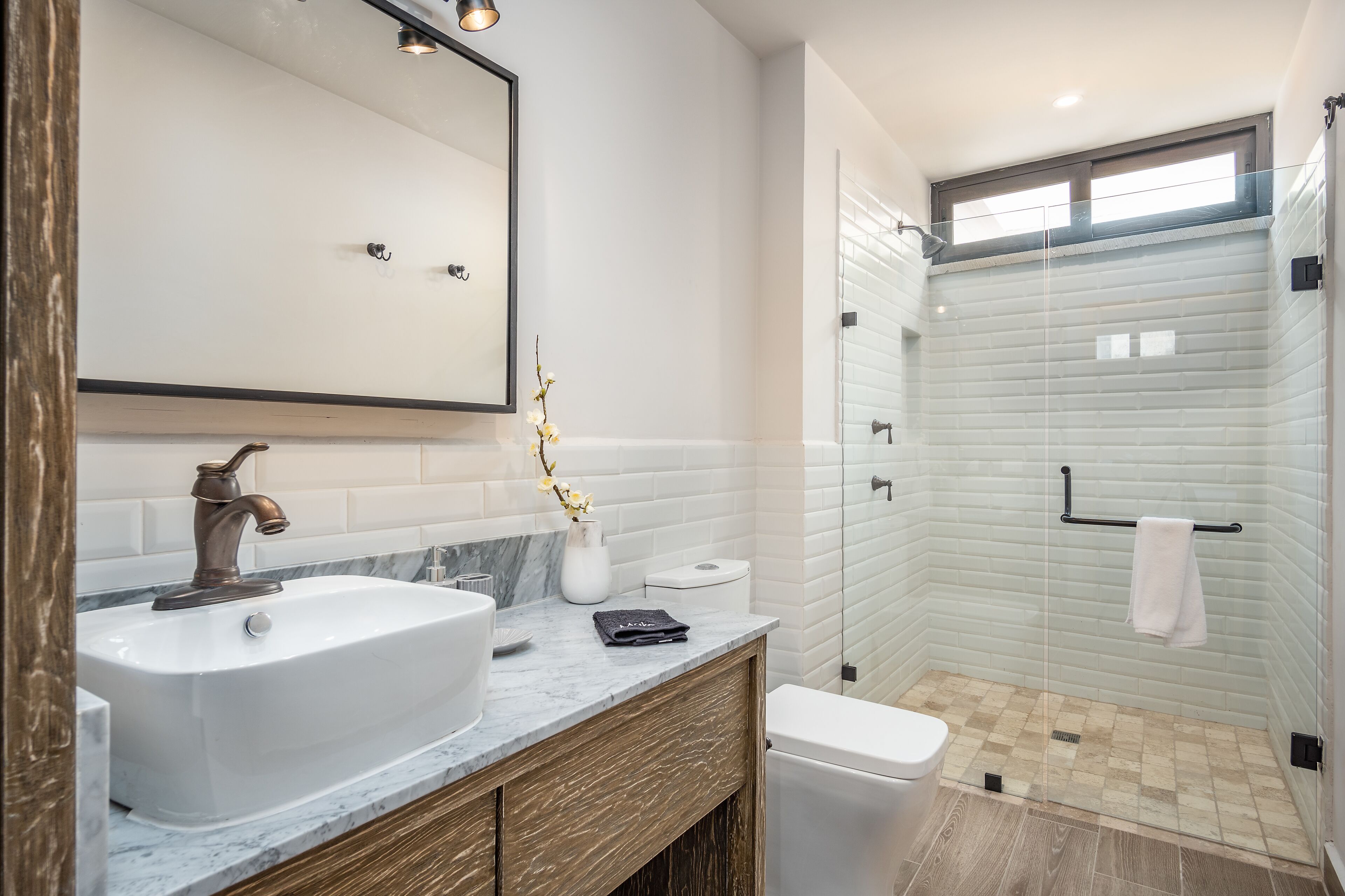 A modern bathroom with a large sink, mirror, and shower area.