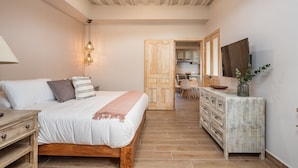 A bedroom with a wooden bed, bedside table, and a TV on a dresser. - Casa Pandurata Luxury Apartments in Centro, San Miguel de Allende (San Miguel de Allende)