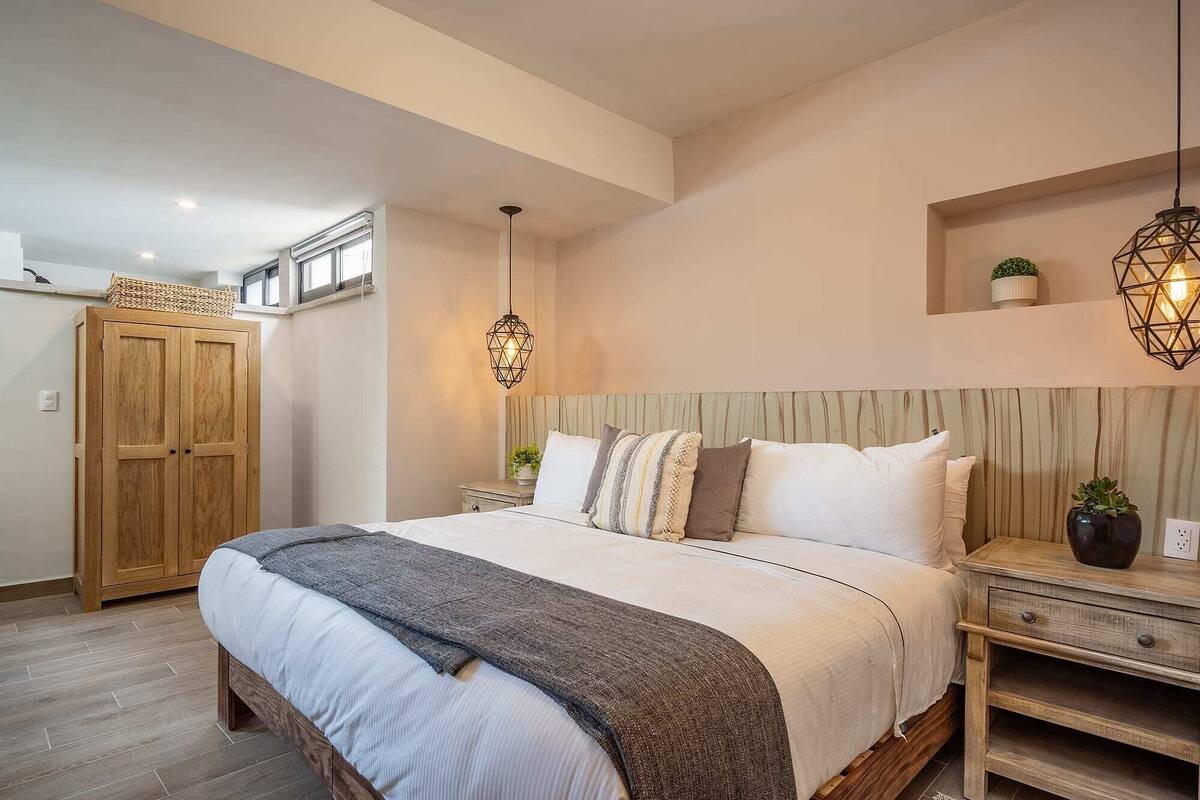 Een slaapkamer met een groot bed, een houten garderobe en een nachtkastje met een lamp.