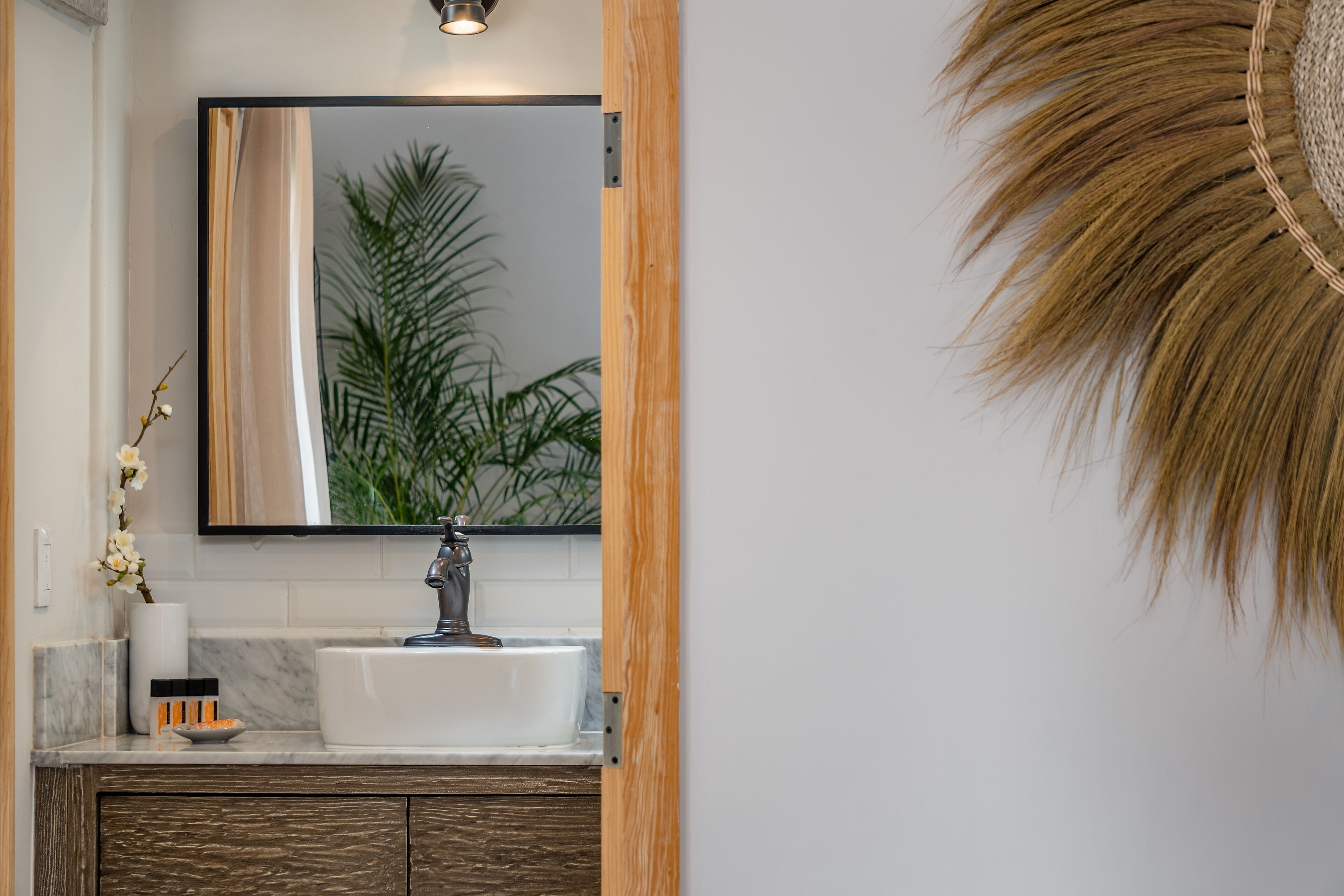 A modern bathroom with a white sink, a large mirror, and a wooden cabinet.