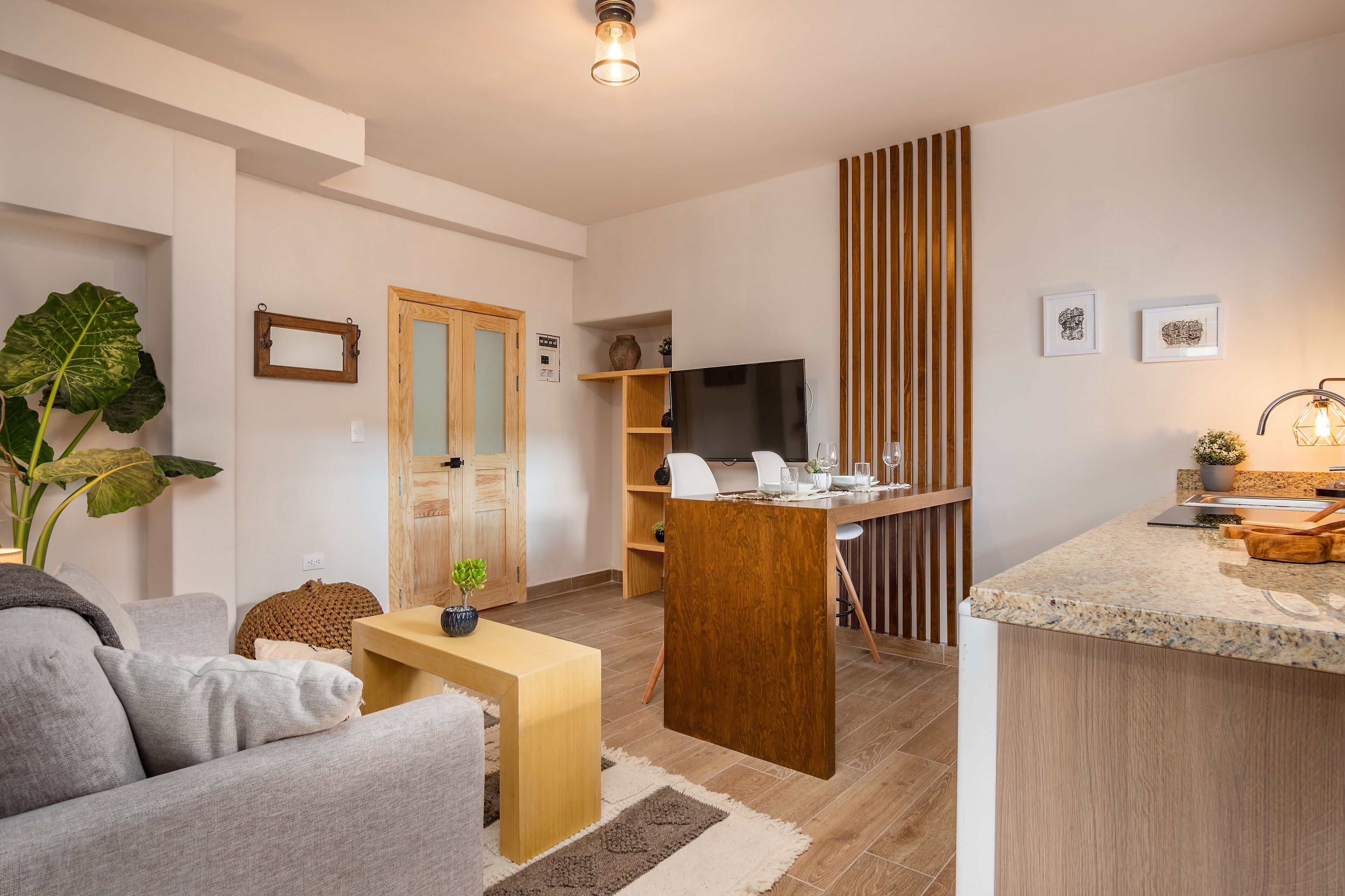Una sala de estar moderna con un sofá, una mesa de centro y un comedor con una mesa y sillas de madera.