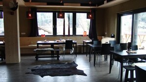 Una habitación amplia con un gran ventanal, piso de madera y alfombra de cuero negro.