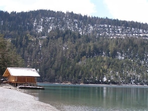 A wooden cabin by a calm lake with a forested mountain backdrop. - Brabander Alm (Biberwier)