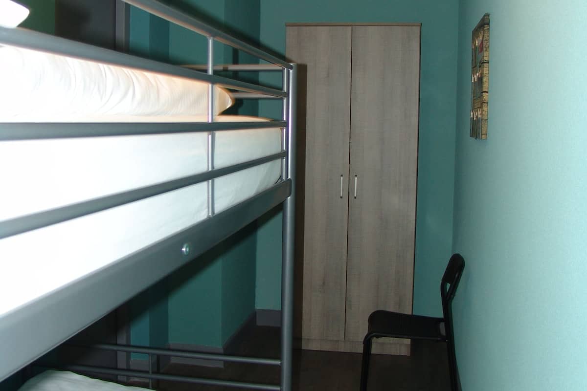 Una camera del dormitorio con letti a castello, un'armadio e una sedia.