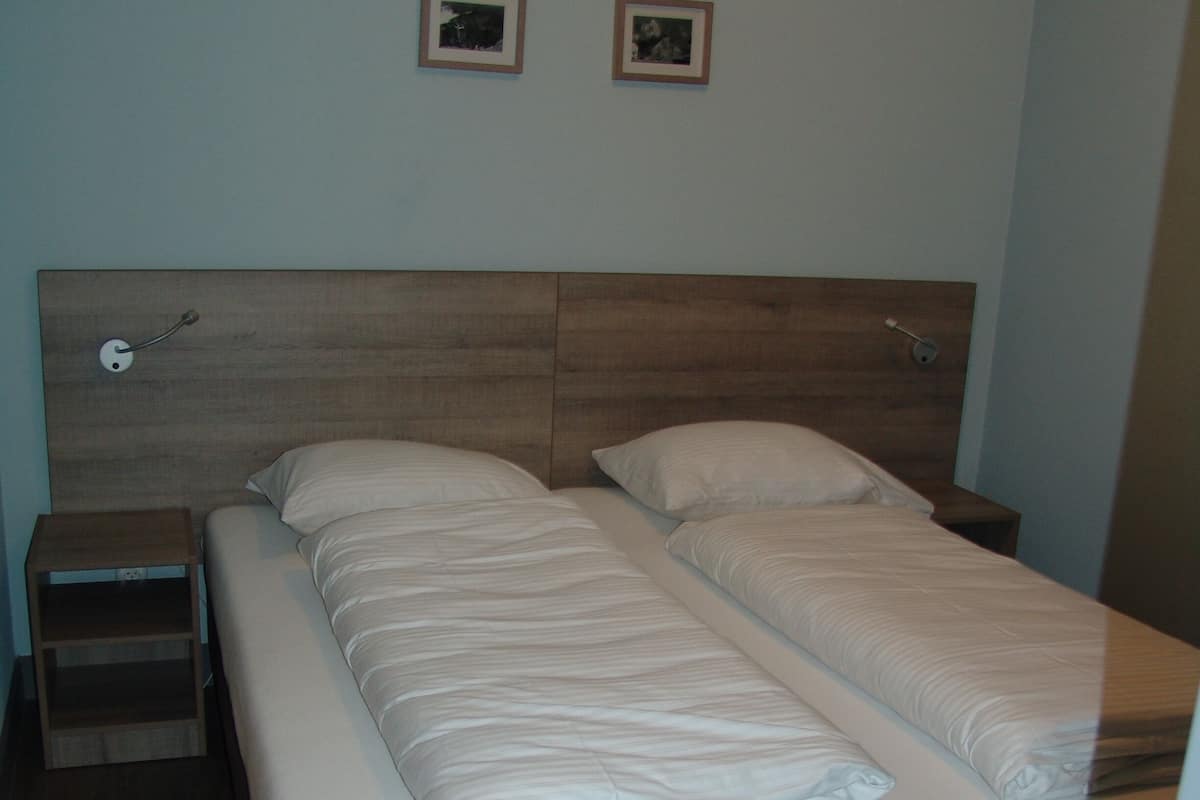 Un letto matrimoniale con una testiera in legno, due comodini e due quadri appesi al muro.