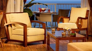 A cozy outdoor seating area with wicker chairs and a wooden table, featuring a view of the ocean. - Amazing 1BR Condo in The Cliffs (Princeville)