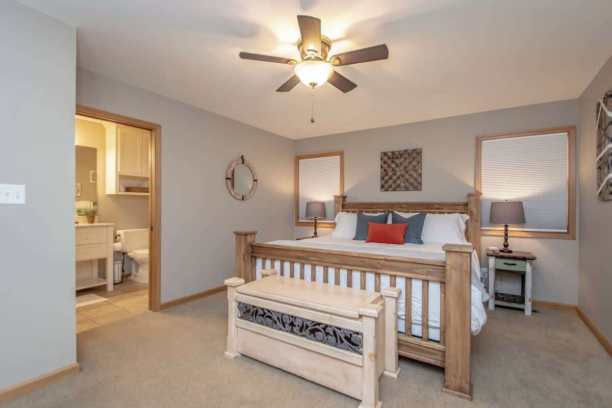 A bedroom with a bed, bedside tables, a ceiling fan, and a window with blinds.