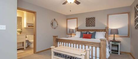 A bedroom with a bed, bedside tables, a ceiling fan, and a window with blinds.