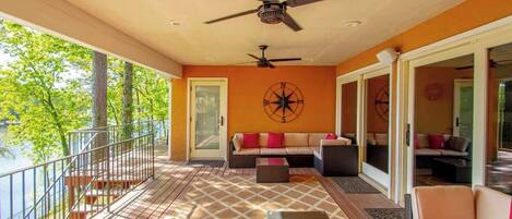A covered outdoor seating area with a ceiling fan, a compass wall decoration, and a view of trees and water.