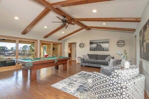 Un grand espace de vie comprenant une table de billard, un canapé et un ventilateur de plafond.