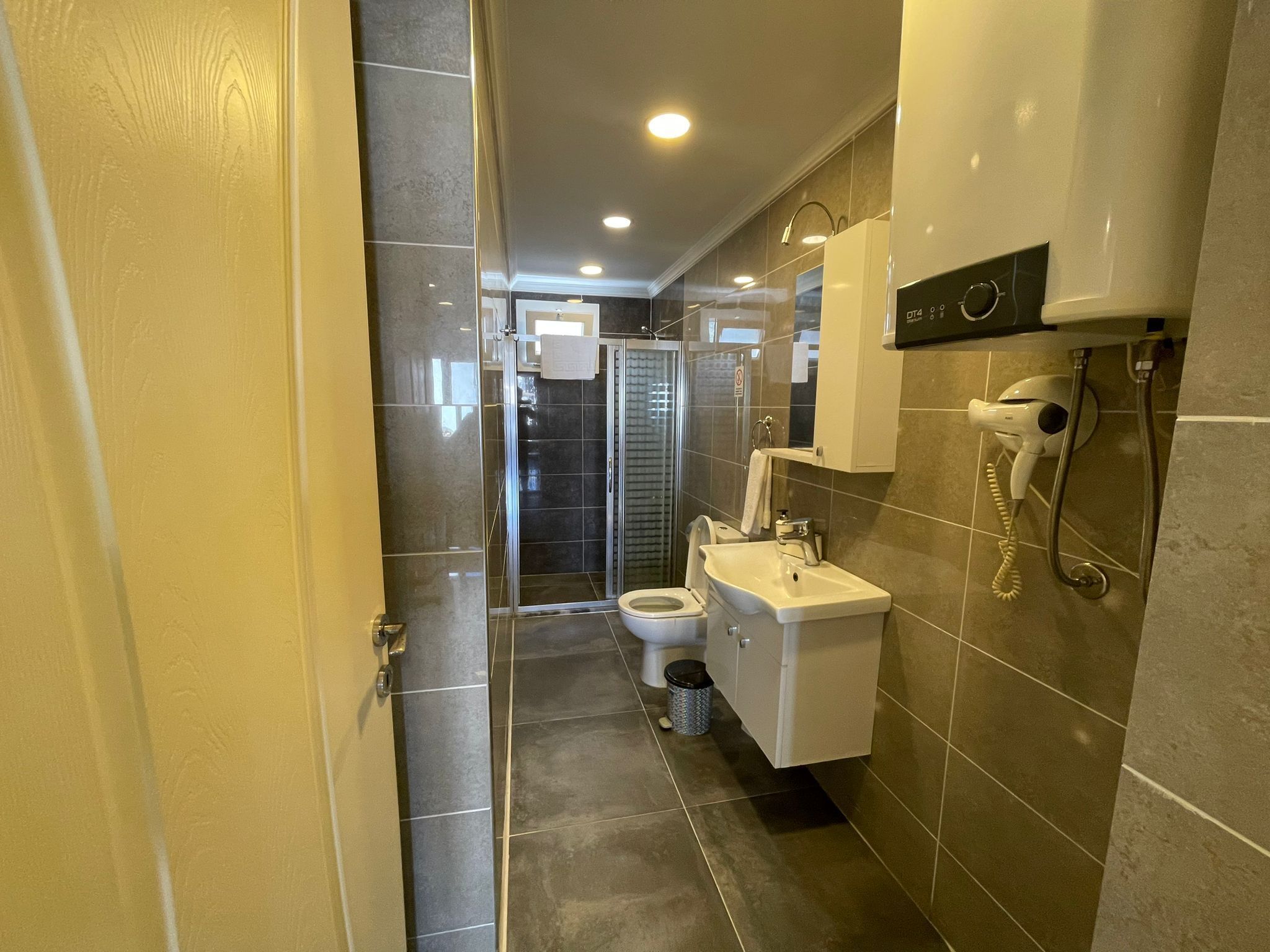 A modern bathroom with a glass shower enclosure, a toilet, and a sink.