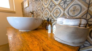 A bathroom with a large white bowl sink, a towel basket, and toiletries on a wooden countertop. - Masseria Ferarelli - "Rizzeddrha" Room with Patio (Diso)